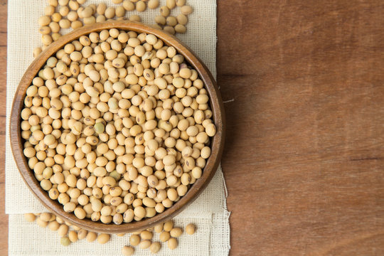 Soybeans in wooden bowl putting on linen and wooden background.