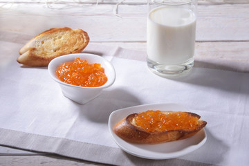 Morning Breakfast set with orange jam on bread toast and milk in glass.
