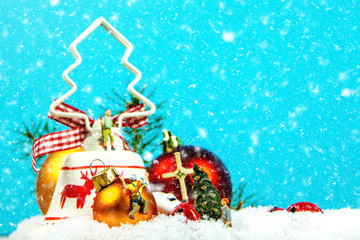 Christmas decoration with snow falling and miniature figurines on blue background