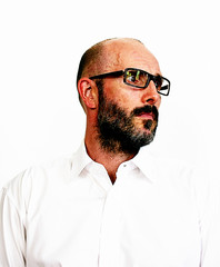 Bearded man with eye glasses in white shirt.