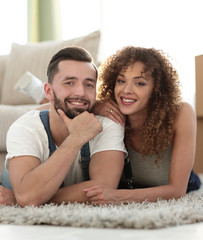 Happy couple lying on the carpet on the blurred background