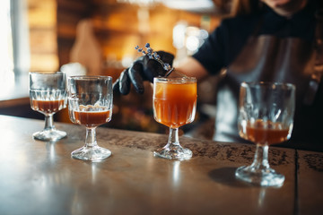 Female bartender prepares alcoholic coctail in pub