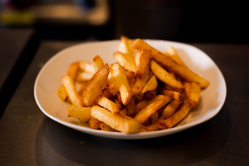 French fries on a plate, isolated on white background.
