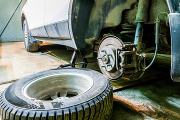 Mechanician changing car wheel in garage. Man exchanging tire. Tire service. Tire fitting.