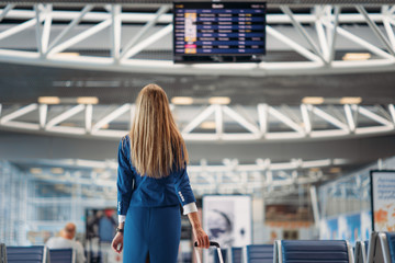 Sexy stewardess looks at scoreboard in airport