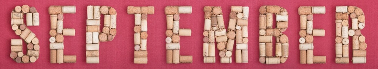 Word September month made of wine corks on red Bordeaux background. Burgundy color and wine berry