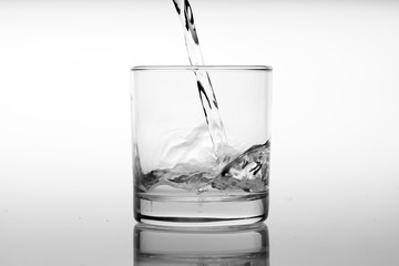 Glass of water with pouring from the bottle, studio shot