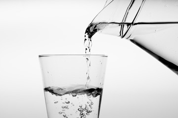 Glass of water with pouring from the bottle, studio shot