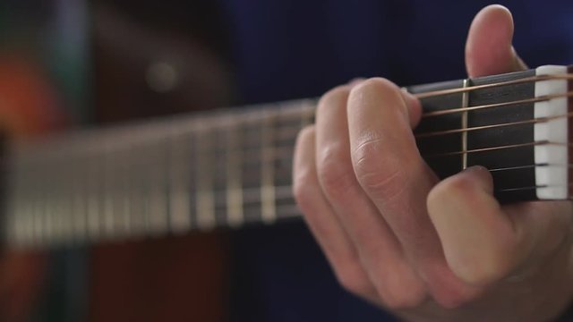 Man's hands playing acoustic guitar, close up