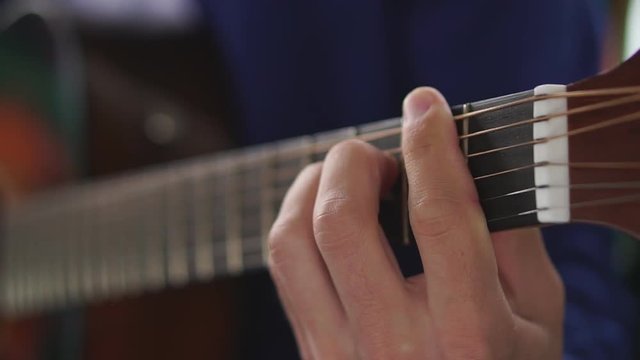 Man's hands playing acoustic guitar, close up