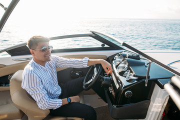Serious handsome business man dressed in classy style, with sunglasses relaxing during sailing on...