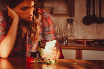 Worried man with rose and mobile phone.