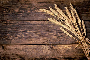 Wheat ears on wooden cracked old table. Sheaf of wheat on vintage background.