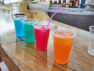 colorfull coctails at the beach bar in summer in plastic glasses