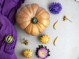 Decorative autumn composition of pumpkins, flowers, yellow peppers on a light background, top view, halloween