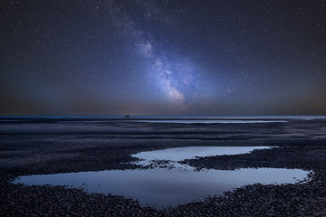 Vibrant Milky Way composite image over landscape of beach at low tide