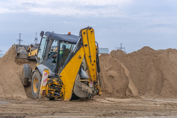 Tractor at the construction site pours a pile of sand