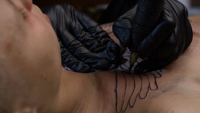 Artist draws a tattoo on the chest of a man close-up