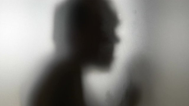 Dancing man behind frosted glass in 4k slow motion 60fps