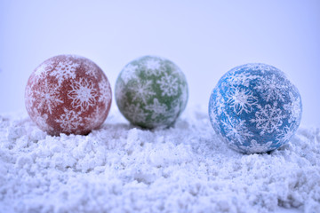 Christmas balls in the snow stock images. Three Christmas balls isolated on snow background. Colorful Christmas balls. Christmas decoration on a blue background
