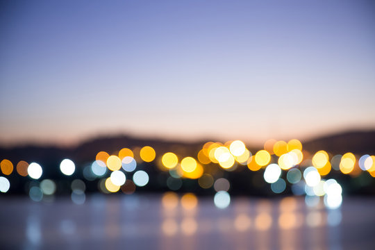 Blurry bokeh light of the riverside town in twilight time. beautiful cityscape at night. image for background, walllpaper and copy space.