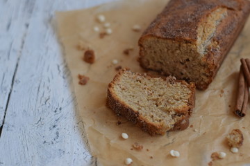 Banana cake with cinnamon and white chocolate on a white wooden background