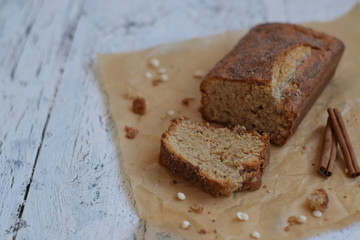Banana cake with cinnamon and white chocolate on a white wooden background