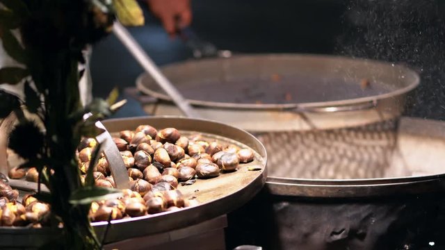 Cooking chestnuts on a street grill. Close up view of roasted chestnuts at street market. 4K (UHD).