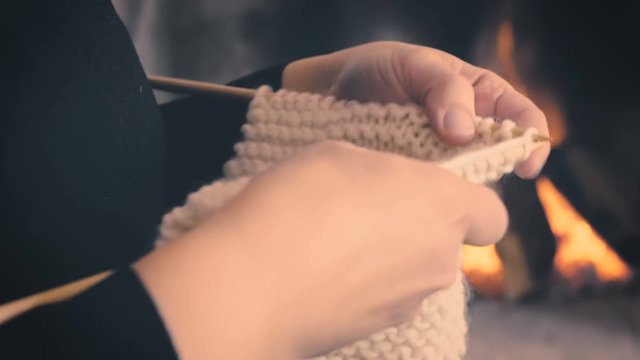 Woman hands knitting on winter fireplace pan