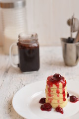 Syrniki with cherry and chocolate sauce on a white wooden background