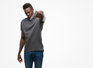 Fototapeta premium Young african american man holding a gun with a confident expression on smart face thinking serious