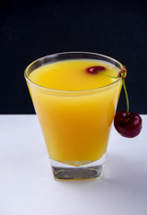 Ripe and juicy cherries with orange juice on a dark background