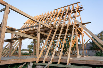 Wooden rafters of a new home under construction at sunset. New house construction interior with exposed framing.