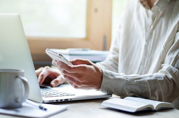 Man working on laptop, with cup of coffee and phone