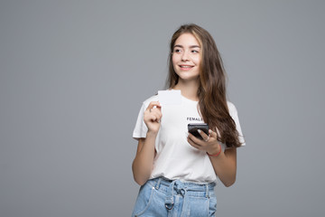 Portrait of a happy girl holding mobile phone and a white card isolated over gray background