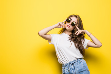 Young trendy woman with sunglasses on a yellow background
