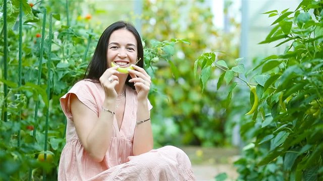 Young woman with basket of greenery and vegetables in the greenhouse. Harvesting time