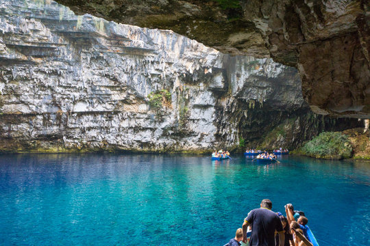 Melissani cave or Melissani lake in Kefalonia Greece. A big part of the roof's cave has fallen revealing a lake with splendid turquoise crystal clear waters. Boats cruising tourists to the lake. 