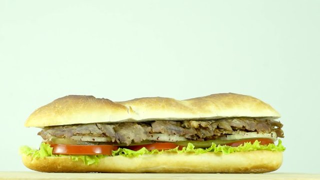 Turkish traditional food beef doner kebab sliced in sandwich bread with tomato, lettuce, pickle and onion.