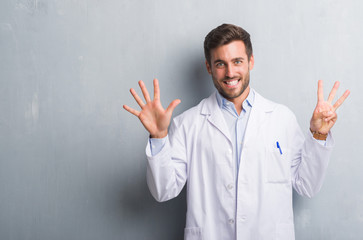 Handsome young professional man over grey grunge wall wearing white coat showing and pointing up with fingers number eight while smiling confident and happy.