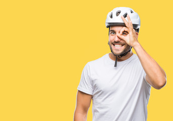Young handsome man wearing cyclist safety helmet over isolated background doing ok gesture with hand smiling, eye looking through fingers with happy face.