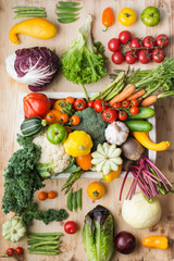Assortment of fresh colorful organic vegetables in white tray on wooden pine table, creative food background, vertical, top view, selective focus