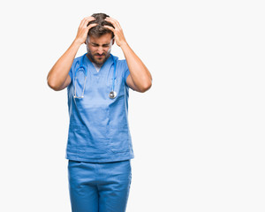 Young handsome doctor surgeon man over isolated background suffering from headache desperate and stressed because pain and migraine. Hands on head.