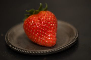 Ripe strawberry on a metal plate