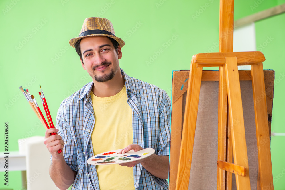 Wall mural Young male artist working on new painting in his studio