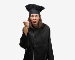 Young hispanic cook woman wearing chef uniform annoyed and frustrated shouting with anger, crazy and yelling with raised hand, anger concept