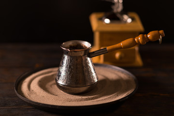 Tiny pot with wooden handle in front of grinder