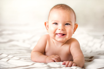 smiling happy newborn infant baby tummy time on bed bright airy copy space childhood