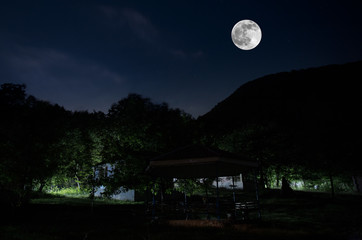 Mountain Road through the forest on a full moon night. Scenic night landscape of dark blue sky with moon. Azerbaijan