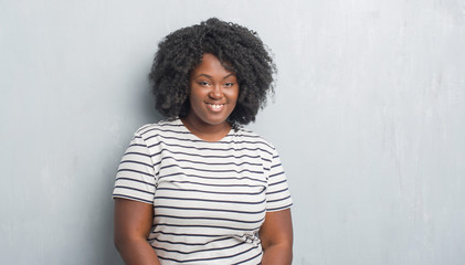 Young african american plus size woman over grey grunge wall with a happy and cool smile on face....